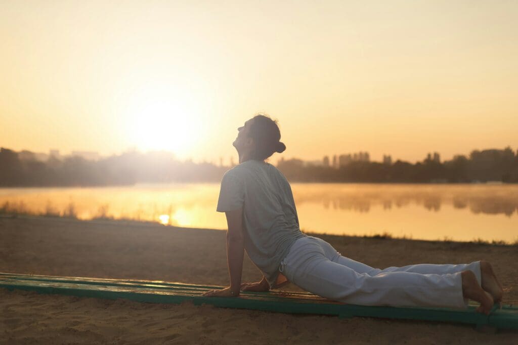 Young athletic men doing yoga on the sand in the park